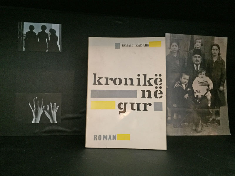 Boek cover 'Kroniek in Steen' met portret familie Kadare in Gjirokastra op de achtergrond.