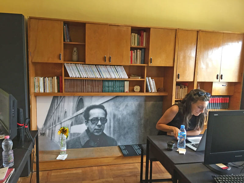 De voormalige slaapkamer van Kadare, nu als museumwinkel ingericht. Grote foto van Ismail en de slaapkamer meubel.