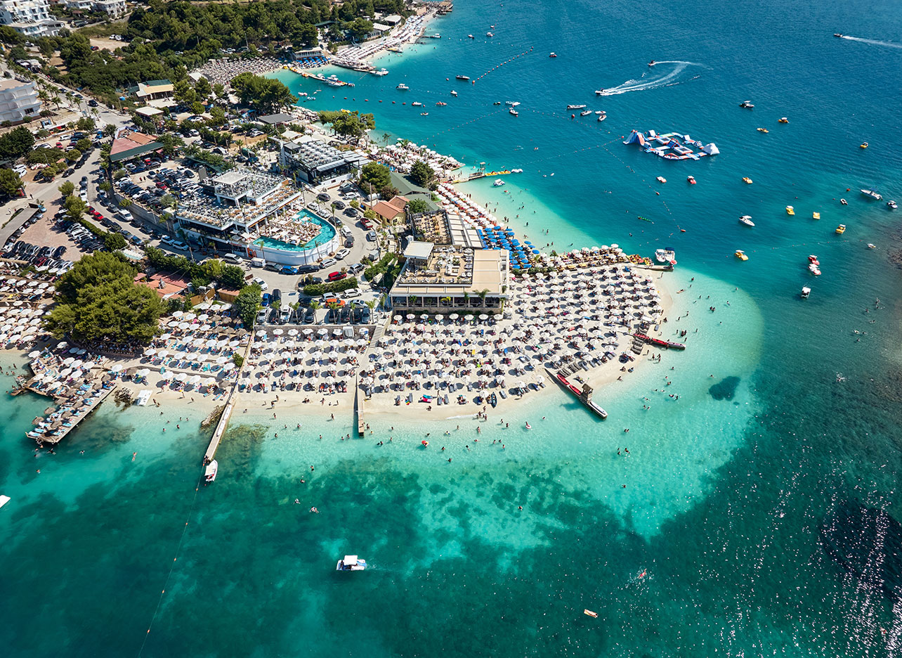 Druk bezocht strand in Ksamil met ligbedden en helder zeewater
