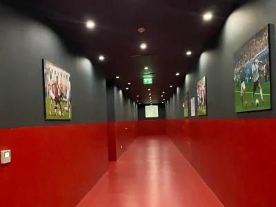 Een lange gang met rood/zwarte muren en een rode vloer in het Air Albania Stadion.