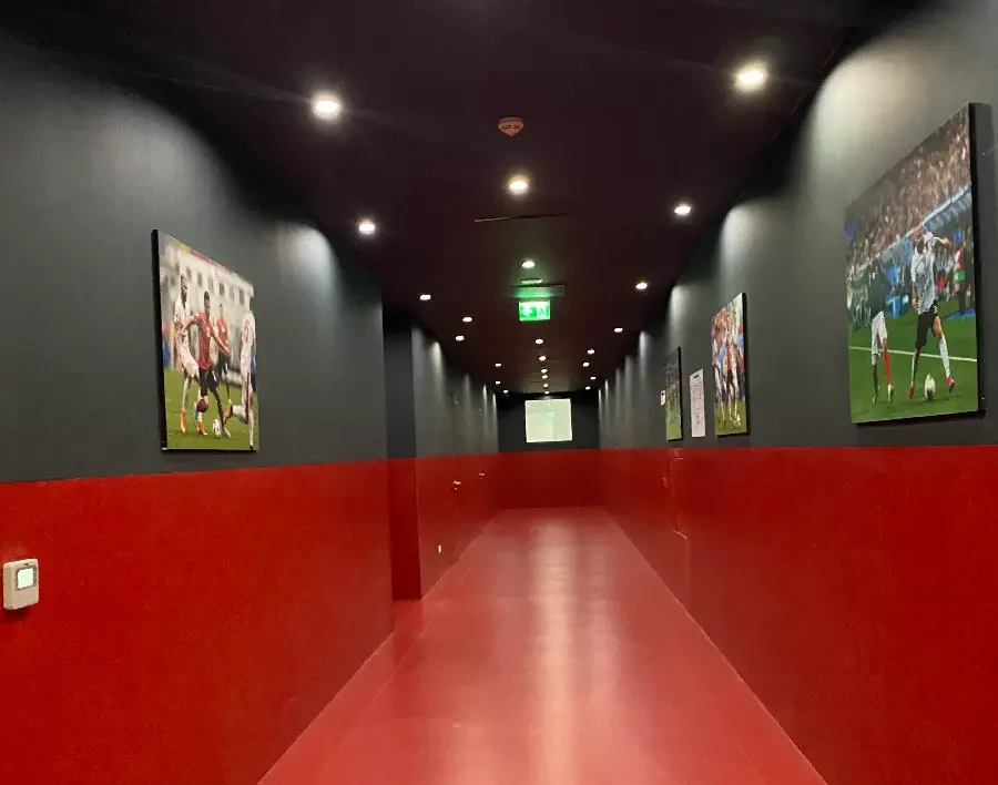 Een lange gang met rood/zwarte muren en een rode vloer in het Air Albania Stadion.