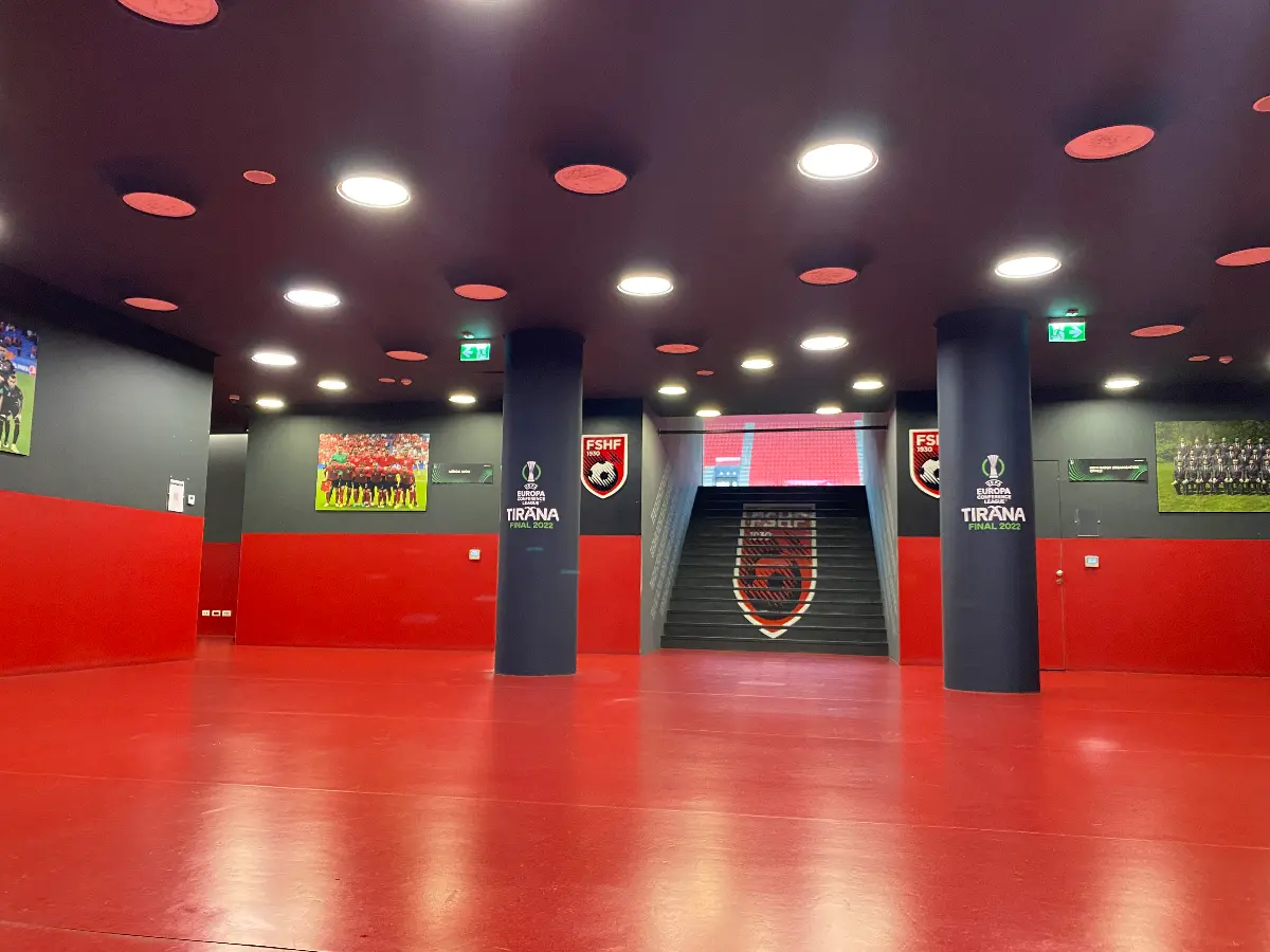 Een rood met zwarte ruimte uitkijkend op een trap en twee pilaren in het Air Albania Stadion.