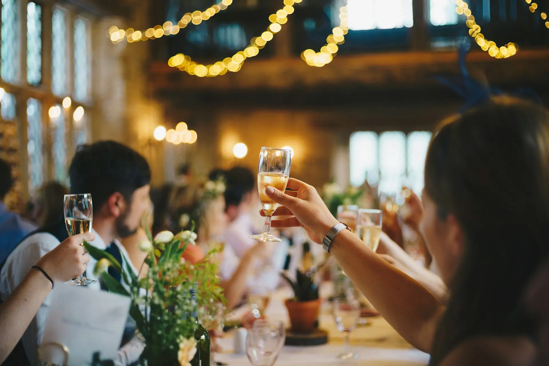 Mensen op een evenement die proosten terwijl ze aan een feestelijk gedekte tafel zitten.