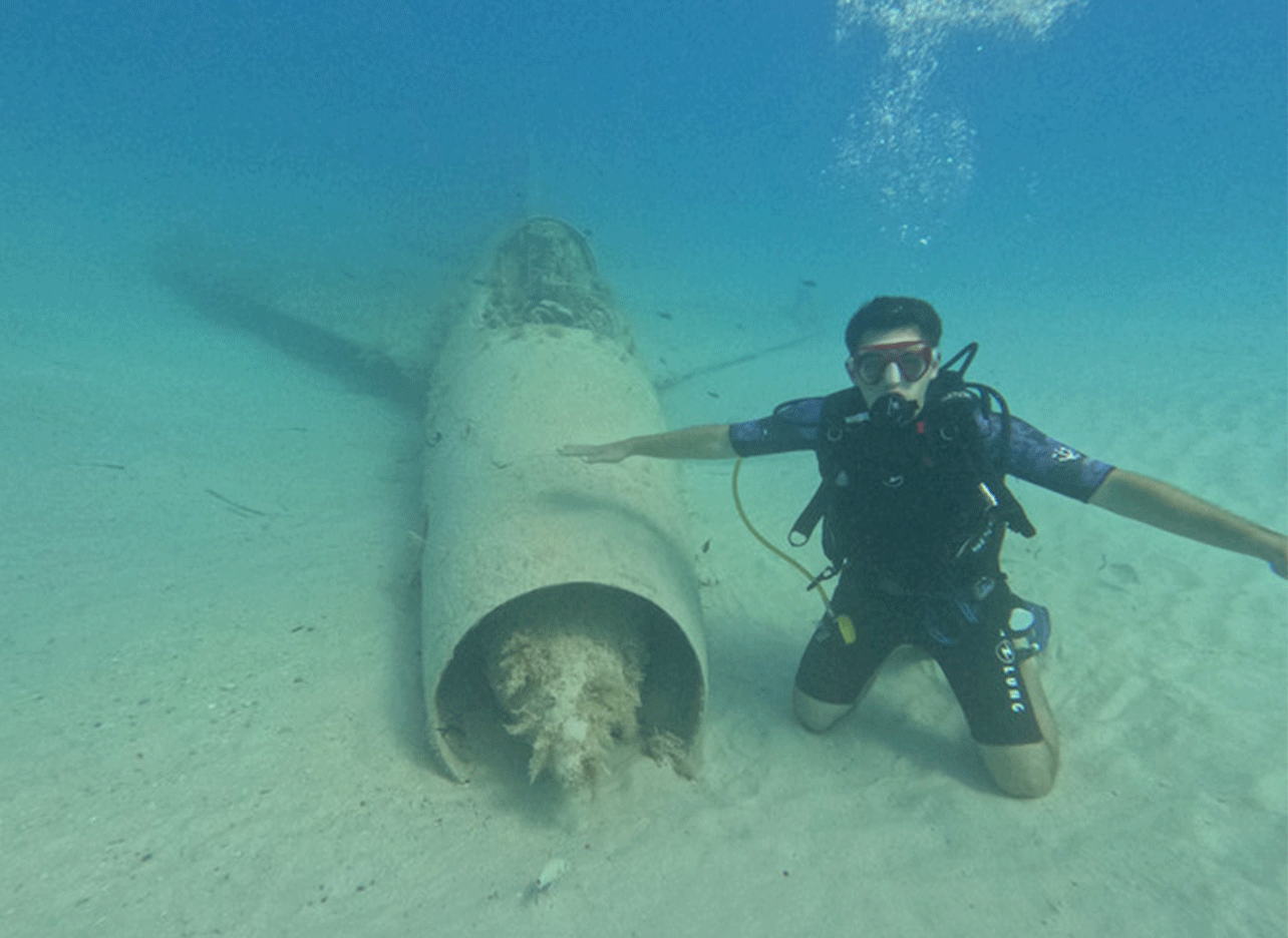 Duiker naast het wrak van een gezonken vliegtuig