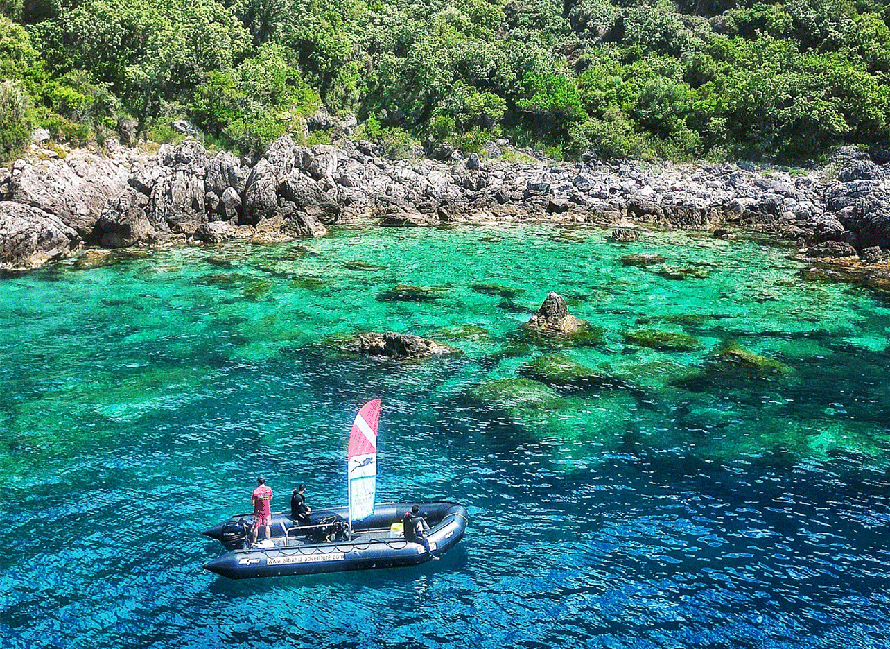 Boot op helderblauw water aan de ruige kust van Palasë.