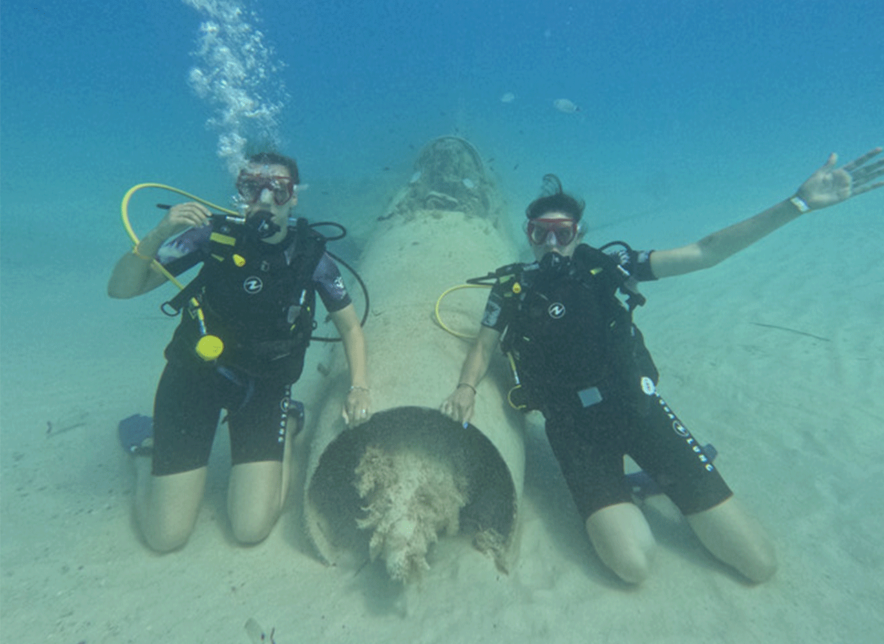 Twee duikers poseren voor een onderwaterwrak