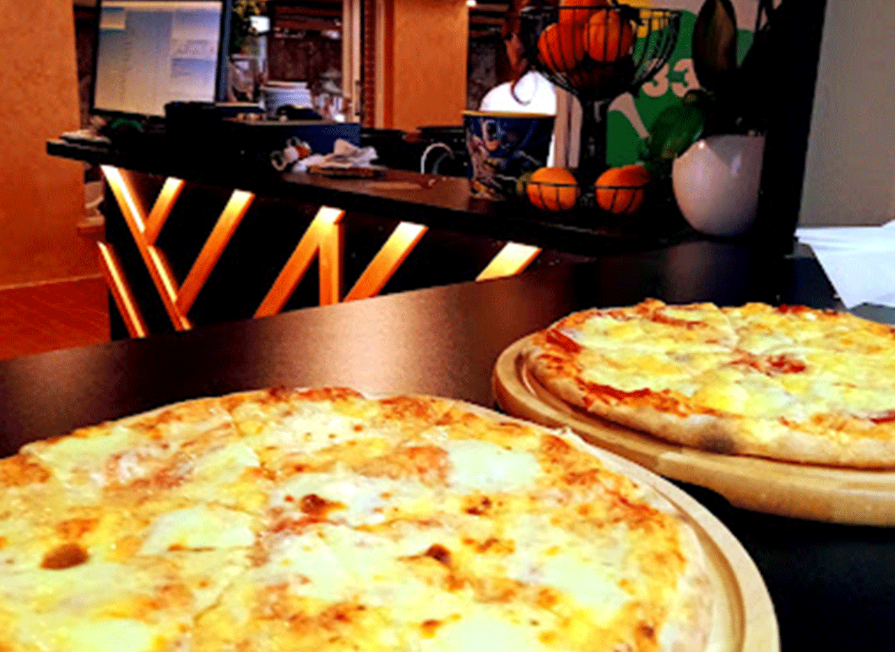 Versgebakken pizza's geserveerd bij het café van Kaartbaan Saranda.