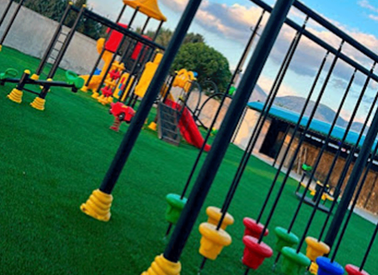 Moderne speeltoestellen op kunstgras bij Kaartbaan Saranda.