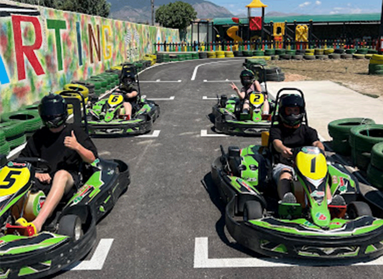 Kinderen racen met helmen op de baan van Kaartbaan Saranda.