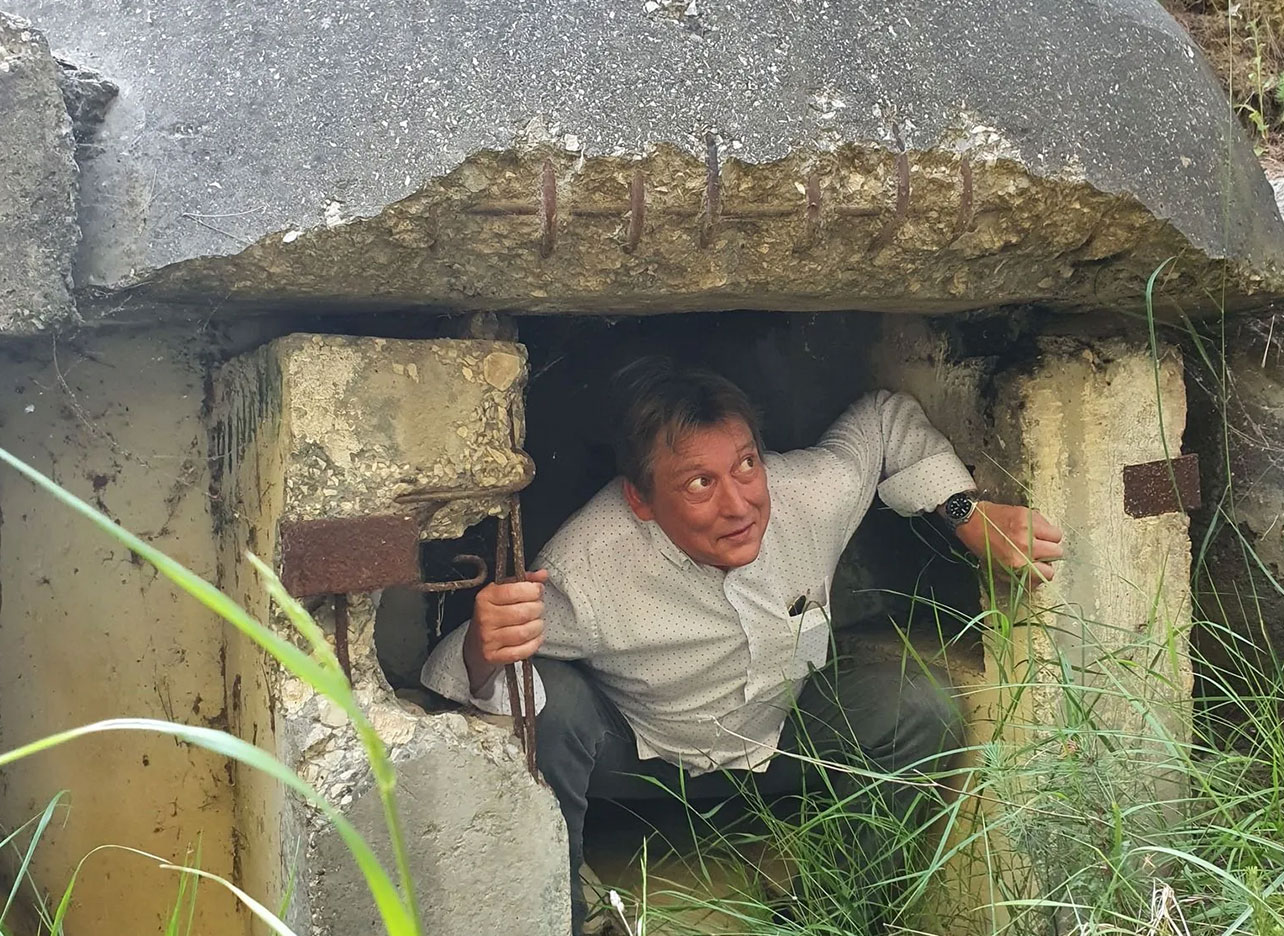 Bunker Albanië: Man komt glimlachend naar buiten uit een oude Albanese bunker.