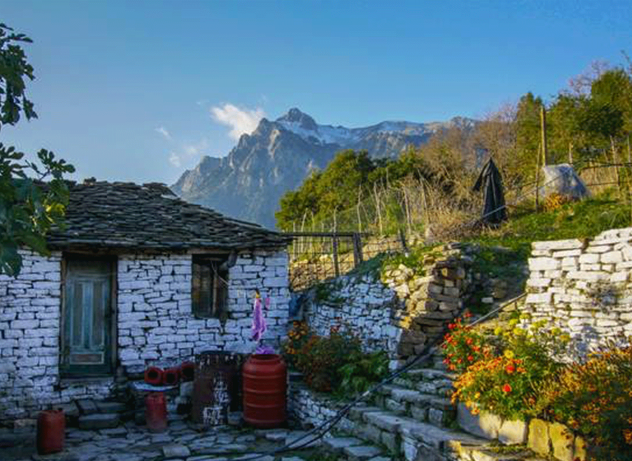 Traditioneel stenen huis in een dorp van Zagoria met hoge bergen op de achtergrond.