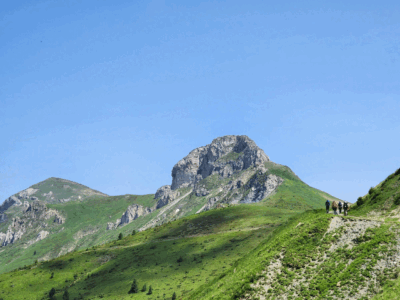 Wandelaars op een bergpad met de groene toppen van Zagoria aan de horizon.