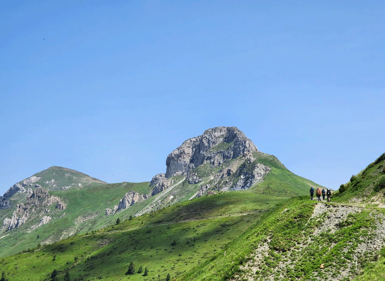 Wandelaars op een bergpad met de groene toppen van Zagoria aan de horizon.
