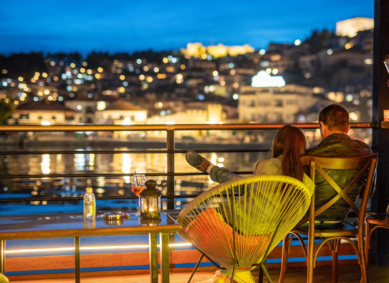 Romantisch stel op het dek, genietend van het uitzicht op de verlichte stad.