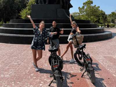 Vlora-Fietstour Vrolijke toeristen met fietsen bij het monument, klaar om de stad te verkennen.