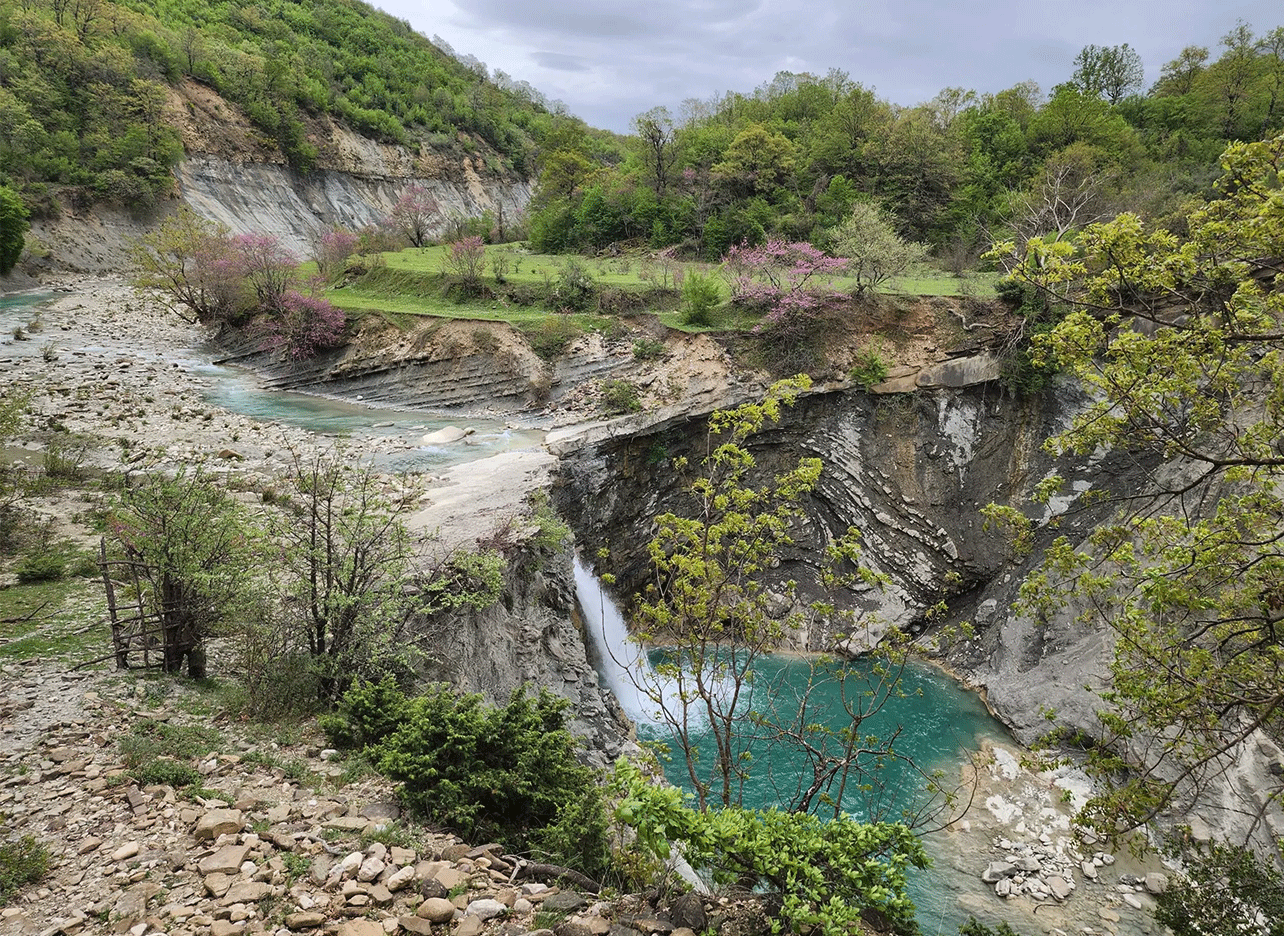 Waterval en turquoise rivier in de Zagoria-vallei, omgeven door lentegroen.