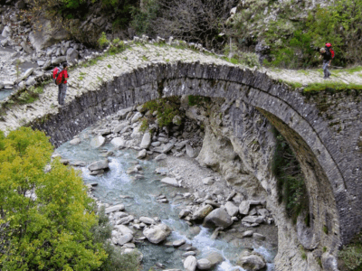 Ottomaanse boogbrug over de rivier van Zagoria met wandelaars die oversteken.