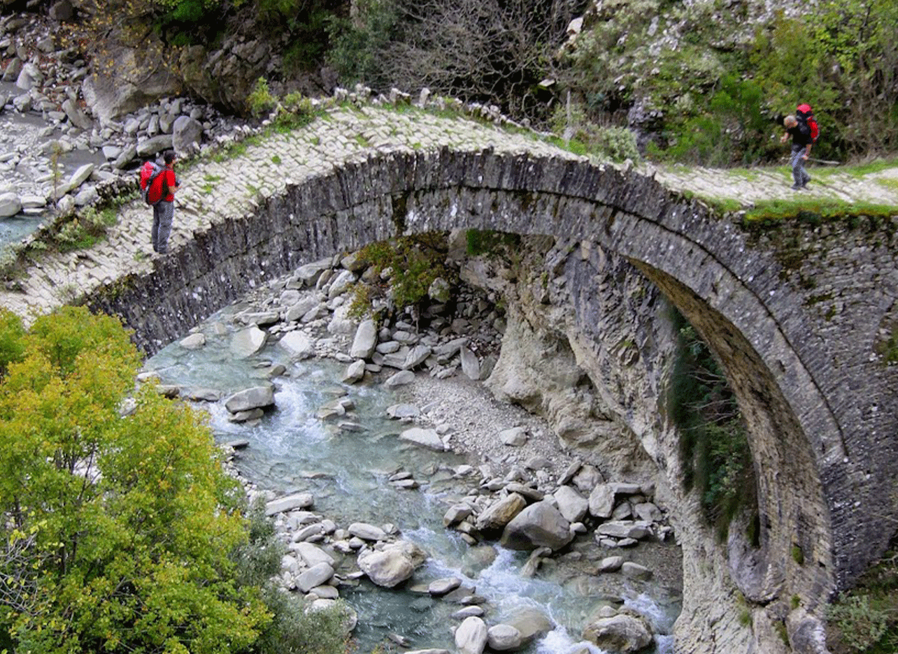 Ottomaanse boogbrug over de rivier van Zagoria met wandelaars die oversteken.