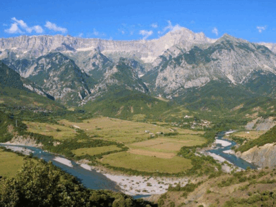 Panoramisch uitzicht over de Vjosa-rivier en vallei, omringd door indrukwekkende bergen.