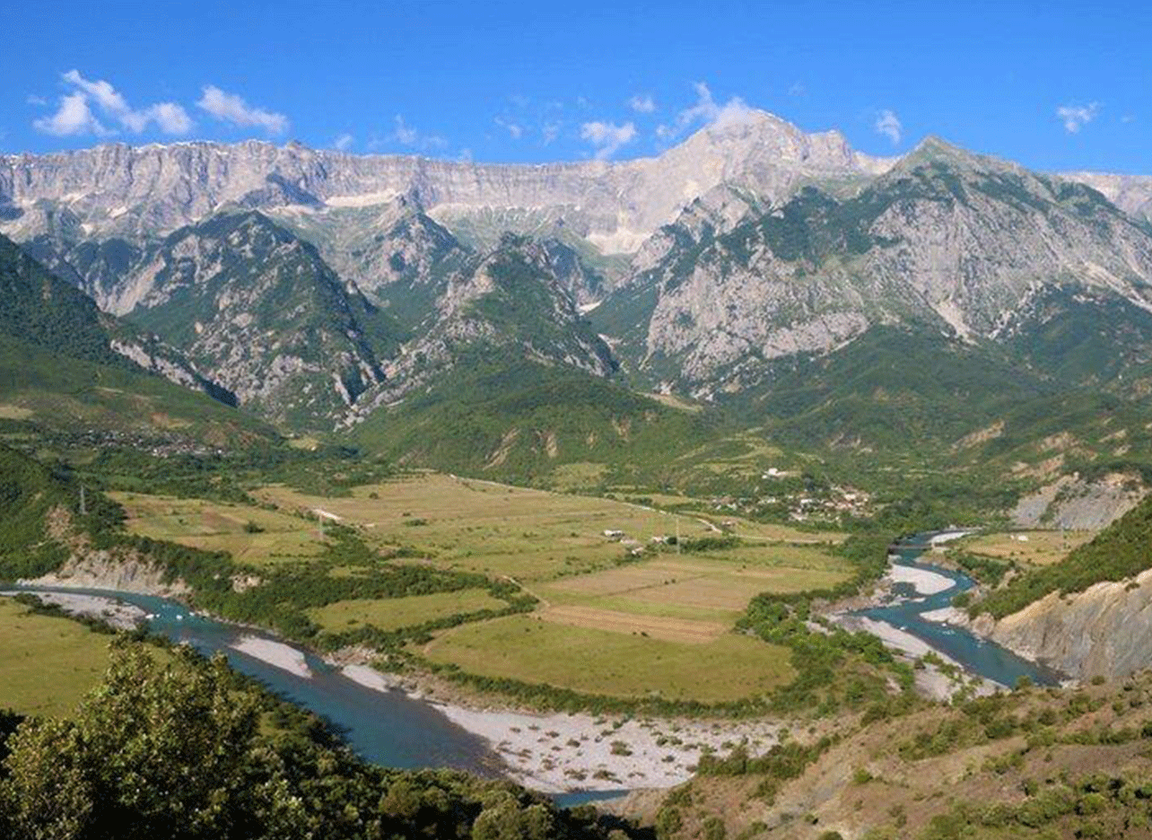 Panoramisch uitzicht over de Vjosa-rivier en vallei, omringd door indrukwekkende bergen.