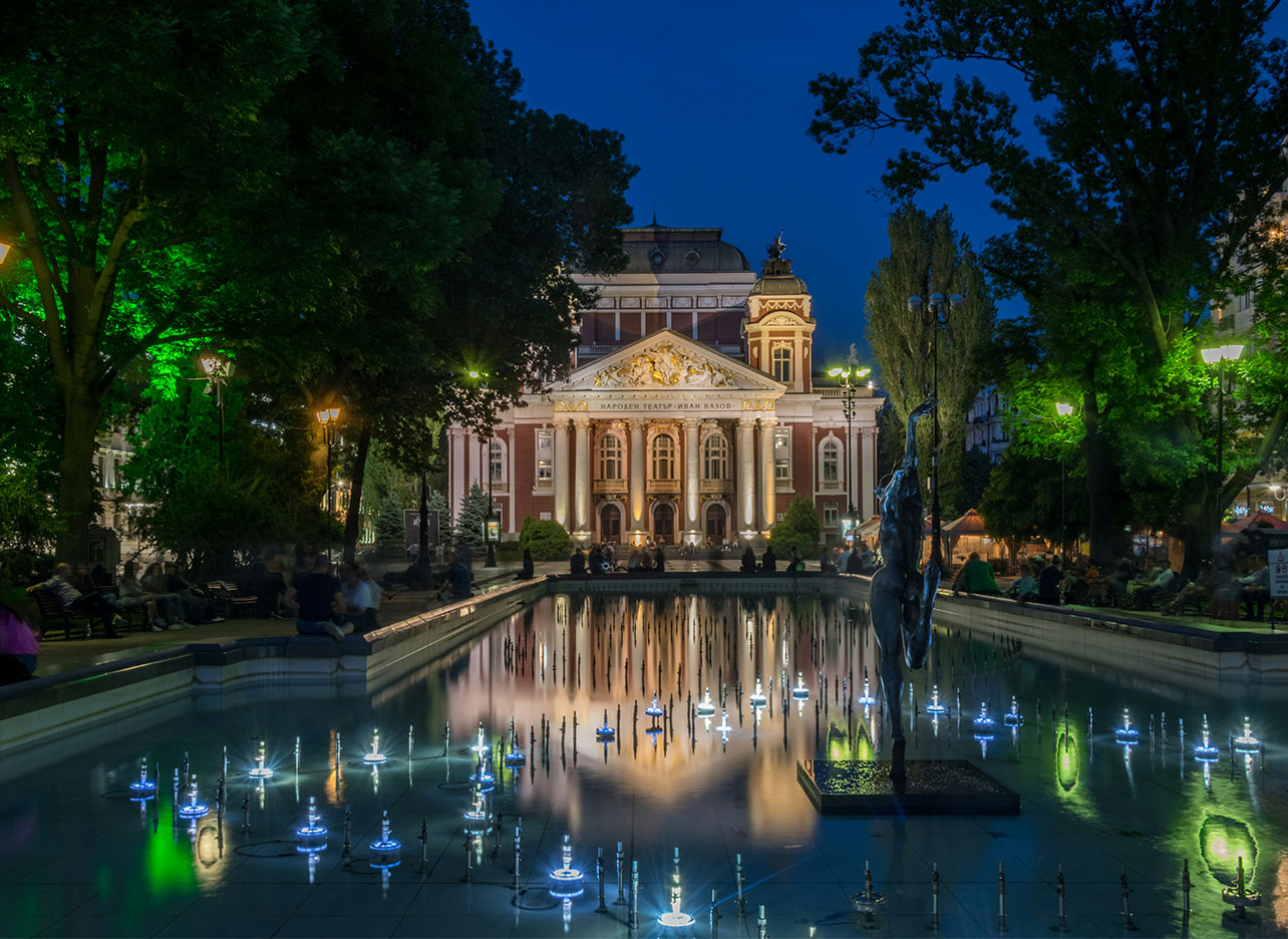 Avondbeeld van het Nationaal Theater met fontein in de tuin.