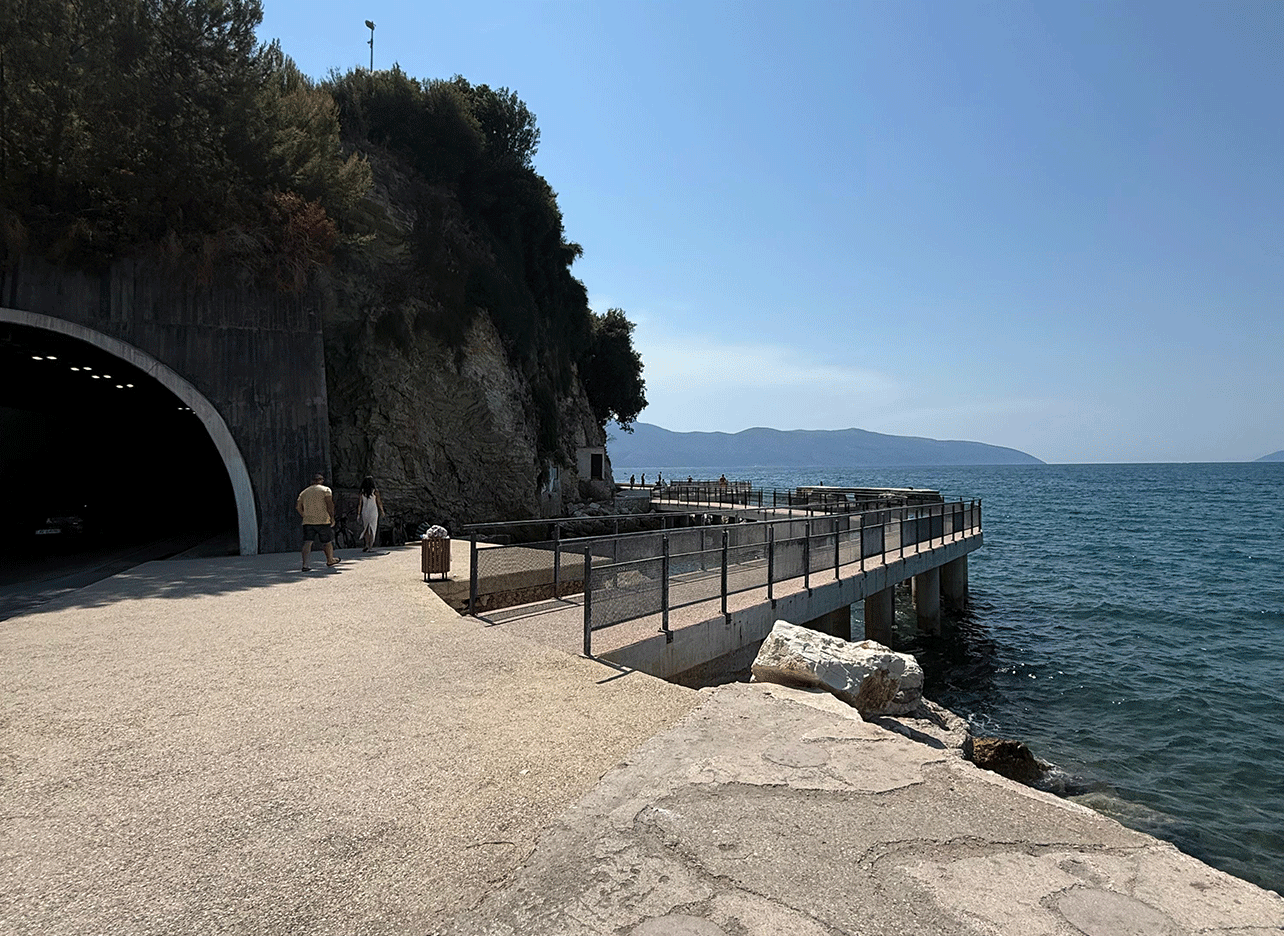 Pad langs de kust bij de tunnel in Vlora met uitzicht op zee en bergen.