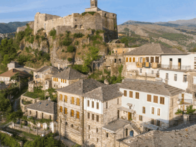 Uitzicht op het kasteel van Gjirokastër boven de historische stad met traditionele huizen met stenen daken, UNESCO-werelderfgoed in Albanië.