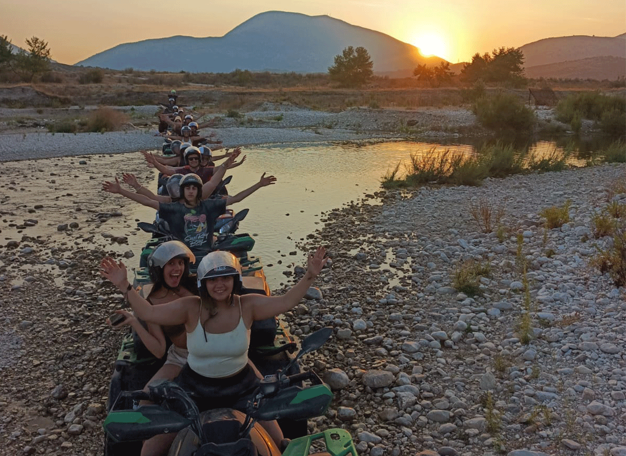 Groep deelnemers op quads die feestvieren bij zonsondergang