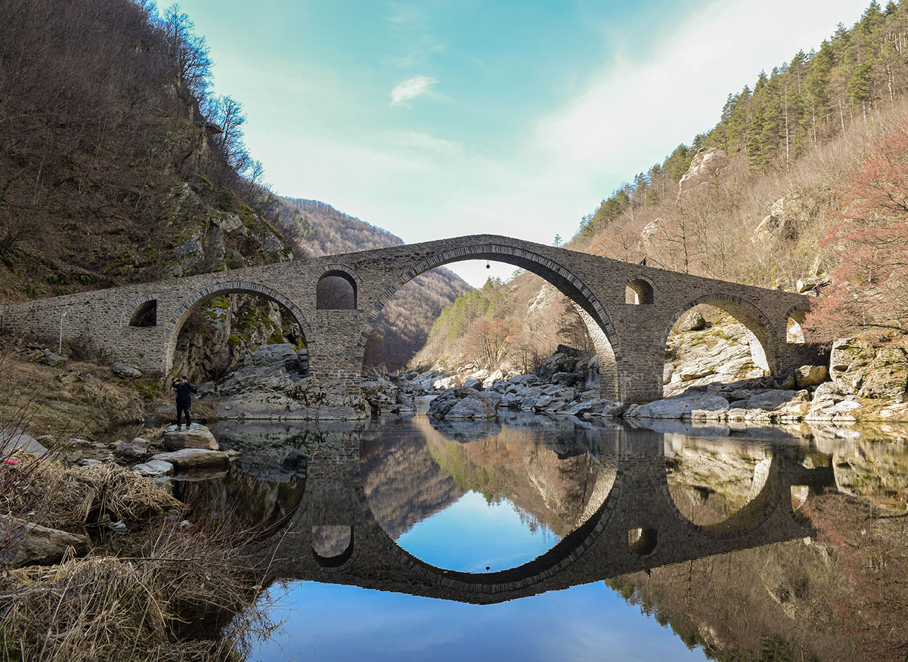 Middeleeuwse stenen brug die prachtig weerspiegeld wordt in het water.
